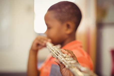 Schoolboy playing flute in classroom at schoolの写真素材
