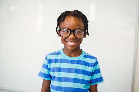 Portrait of happy schoolboy smiling in classroom at school