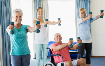 Seniors exercising with weights during sports classの写真素材