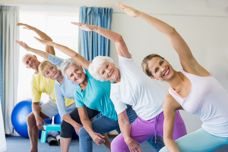 Instructor performing yoga with seniors during sports classの写真素材