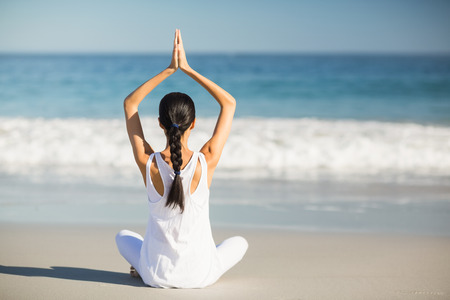 Woman performing yoga on the beachの写真素材