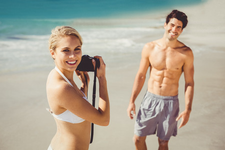Young woman taking picture of her man on beachの写真素材