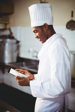 Chef using digital tablet in commercial kitchenの写真素材