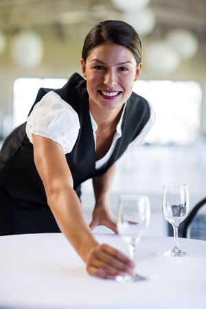 Portrait of smiling waitress setting the table in a restaurantの写真素材