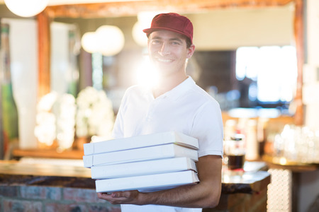 Pizza delivery man holding pizza boxes in restaurantの写真素材