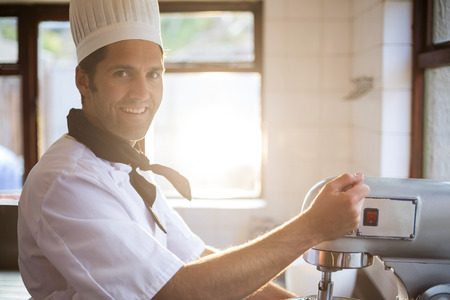 Portrait of chef in commercial kitchen blending the batter in mixing blender