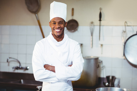 Portrait of happy chef standing with arms crossed in commercial kitchenの写真素材