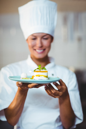 Smiling chef presenting her food in the kitchenの写真素材