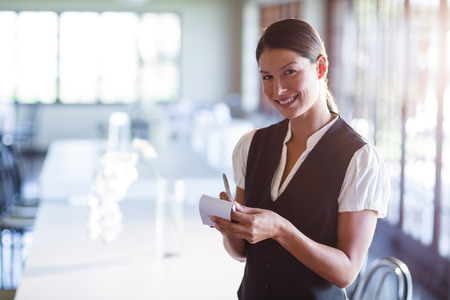 Portrait of smiling waitress taking order in restaurant