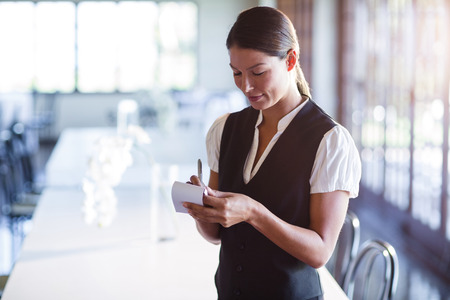 Smiling waitress taking order in restaurantの写真素材