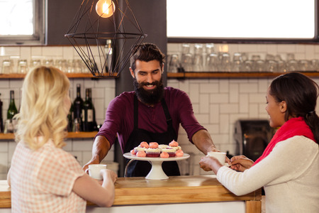 Bartender serving coffee to customers in the barの写真素材
