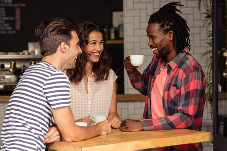 Friends talking together and smiling in cafeteriaの写真素材