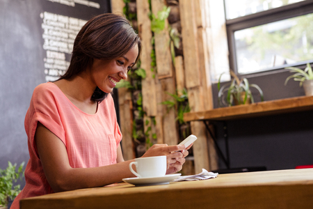 Woman using a smartphone in a cafeの写真素材