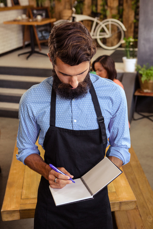 Waiter taking order in his book in the cafeの写真素材
