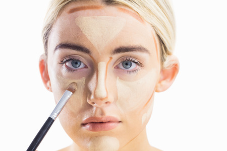 Woman doing contouring on her face in a studioの写真素材