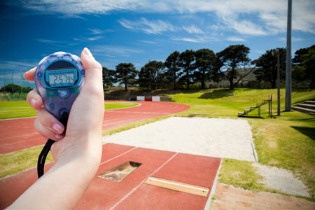Composite image of a woman holding a chronometer to measure performance against high angle view of trackの写真素材
