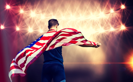 Rear view of sportsman holding an american flag against flash lightの写真素材