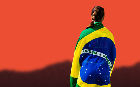 Rear view of sporty woman holding the Brazilian flag against blurred mountainsの写真素材