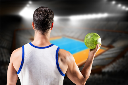Rear view of male athlete holding ball against handball field indoorの写真素材
