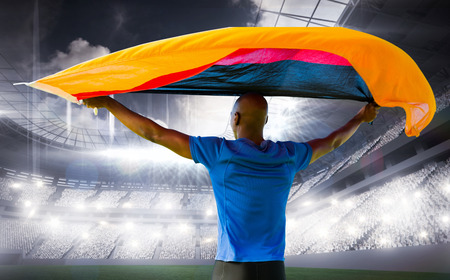 Sporty man holding a German flag against sports arenaの写真素材