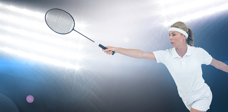 Female athlete playing badminton against spotlightsの写真素材