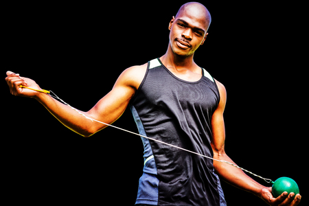 Front view of sportsman holding a hammer  against black backgroundの写真素材