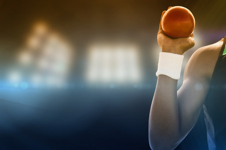 Close up of hand holding a shot against composite image of spotlightの写真素材