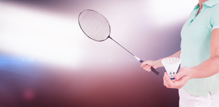 Pretty blonde playing badminton  against spotlightsの写真素材