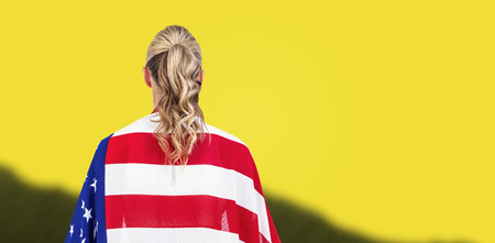 Athlete with american flag wrapped around his body against yellow backgroundの写真素材