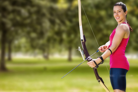 Sportswoman practicing archery against parkの写真素材