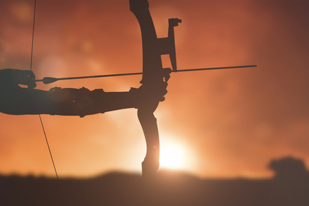 Close up of someone practising archery  against landscape with sunsetの写真素材
