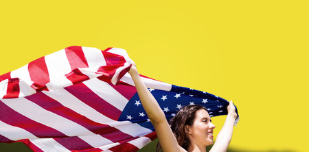 Profile view of sportswoman is raising an american flag  against yellow backgroundの写真素材
