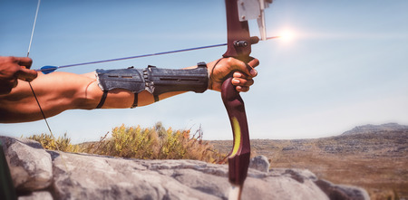 Close up of man stretching his bow against mountain trail