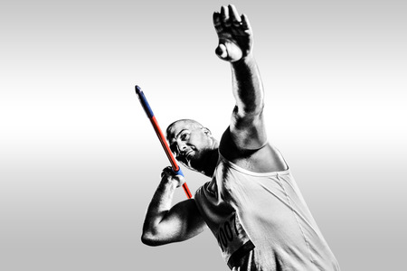 Athlete preparing to throw javelin against grey backgroundの写真素材