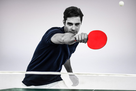 Portrait of male athlete playing table tennis against grey backgroundの写真素材