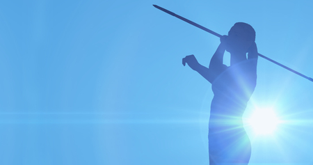 Female athlete throwing a javelin against blue backgroundの写真素材