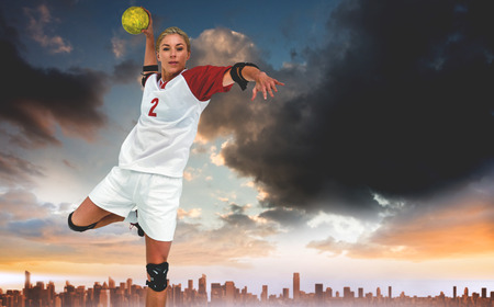 Sportswoman throwing a ball against city on the horizon