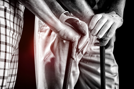 Hands holding golf club against black backgroundの写真素材