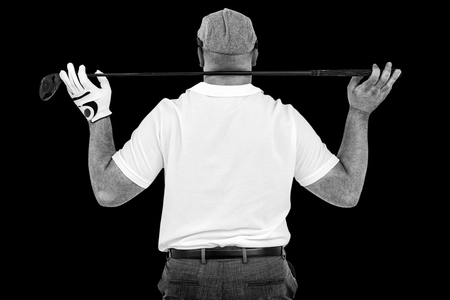 Rear view of golf player holding a golf club against black backgroundの写真素材