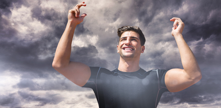 Portrait of happy sportsman  against gloomy skyの写真素材