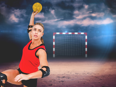 Female athlete throwing handball against dark cloudy skyの写真素材