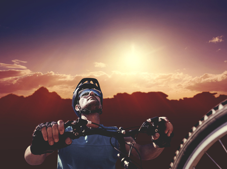 Man cycling with mountain bike against composite image of landscapeの写真素材