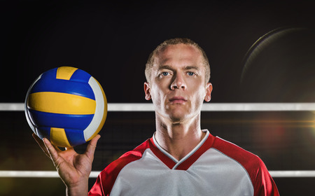 Sportsman holding a volleyball against coloured backgroundの写真素材
