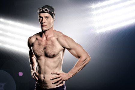 Composite image of swimmer standing with hand on hip against spot lightの写真素材