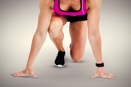 Composite image of female athlete on the start line against a grey background