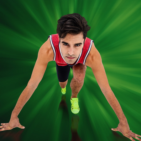 Composite image of male athlete in ready to run position against green background