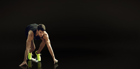 Composite image of sportsman waiting on the starting block against a black backgroundの写真素材
