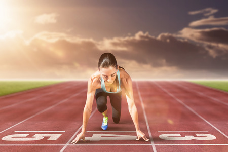 Composite image of sportswoman in the starting block on race track