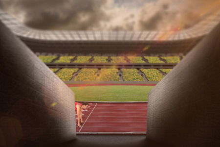 Composite image of confident male athlete in ready to run position in a stadiumの写真素材