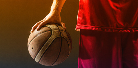 Close up on a basketball held by basketball player on a gymの写真素材